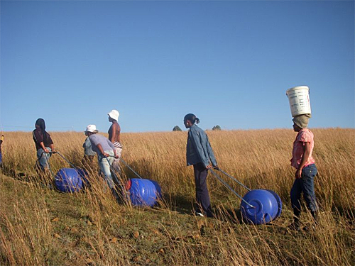 A group of woman using hippo rollers to carry water