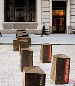 set of turntable bollards across a cobbled street with a man walking on the sidewalk in the background