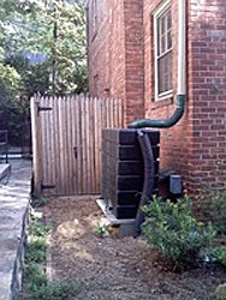 A rain barrel placed discreetly behind a historic house